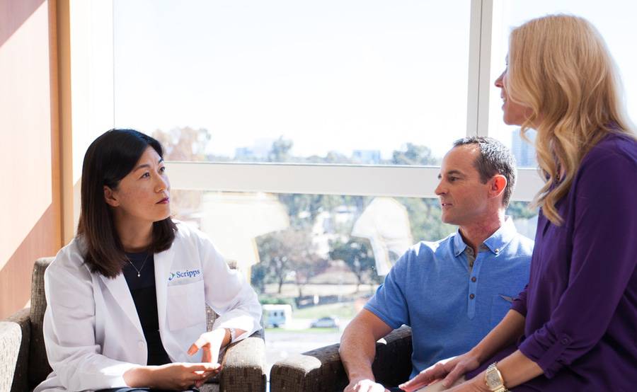 Dr. Kiyon Chung sits with a man and a woman in a bright, sunny room.