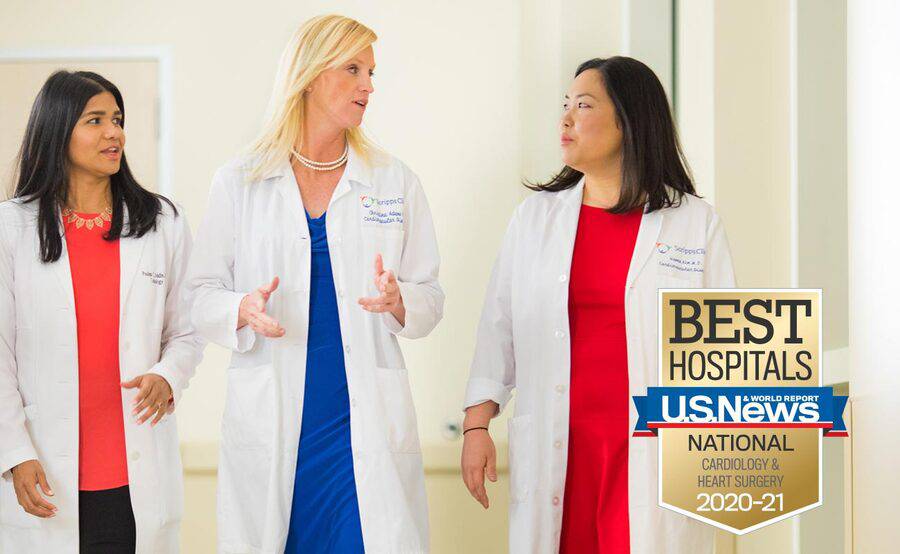 Three female cardiologists talking in a hospital hallway represent the expertise in women's heart care at Scripps.