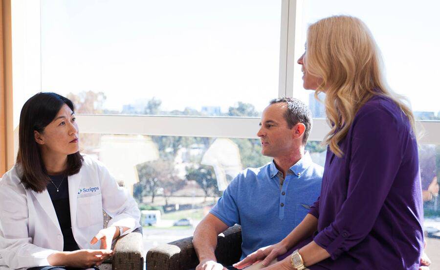 Dr. Kiyon Chung sits with a man and a woman in a bright, sunny room.