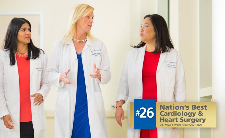 Three female cardiologists talking in a hospital hallway represent the expertise in women's heart care at Scripps.