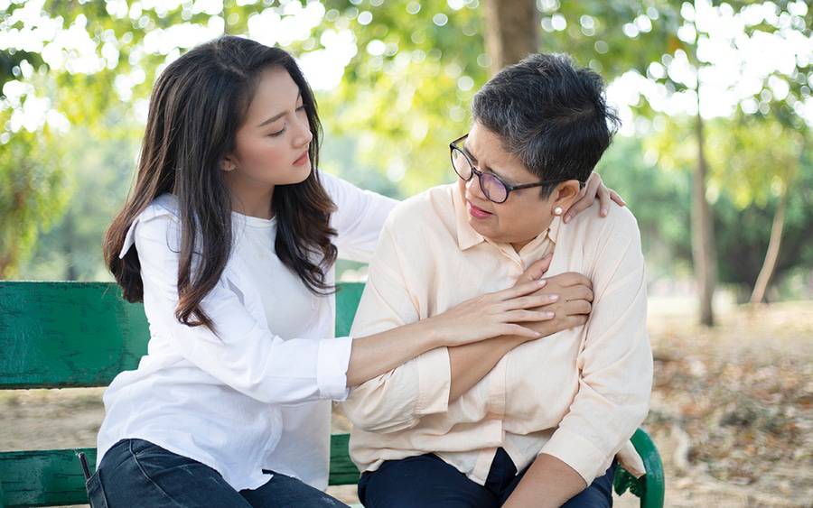 A young woman comforts her mother who thinks she has indigestion but may be experiencing a heart attack.