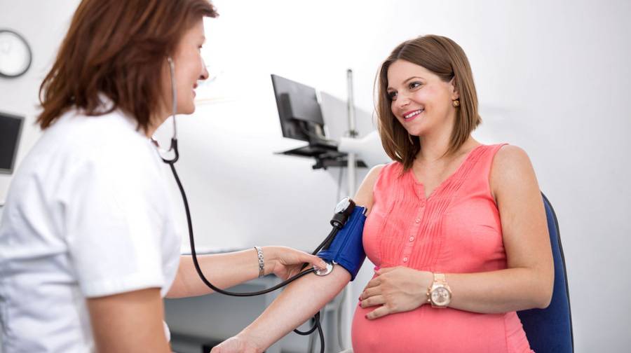 A health care provider checks a pregnant woman's blood pressure.