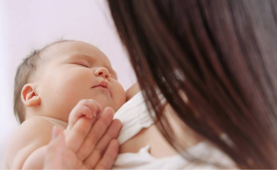 A mother holds her sleeping baby.