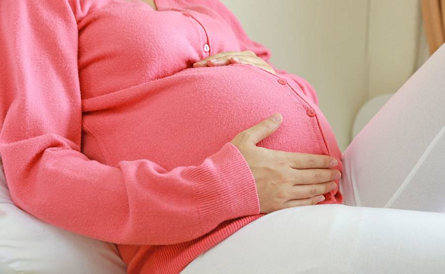 A pregnant woman sitting on a sofa.