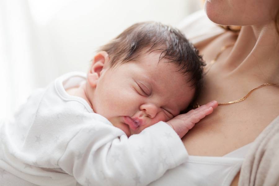 A mother holds her sleeping baby.