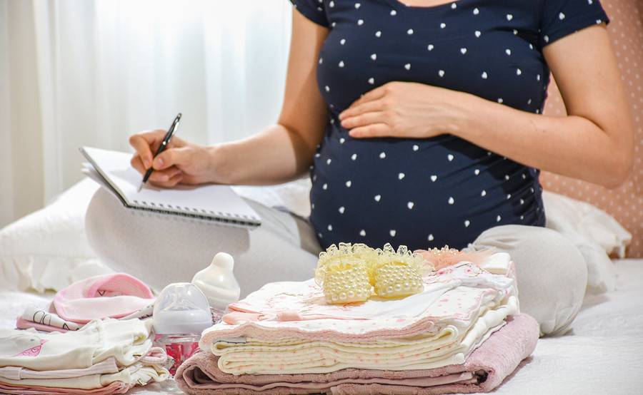 A pregnant woman sitting with a notepad.