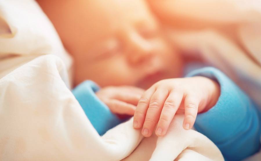 A newborn baby sleeps while wrapped in a soft blanket, representing the sensitive neonatal intensive care (NICU) Scripps provides in partnership with Rady Children’s Hospital. 