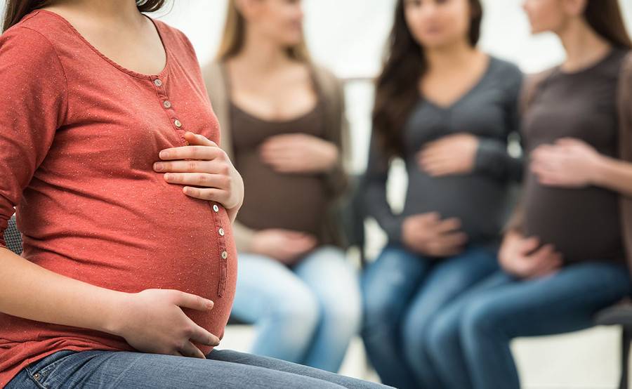 Four pregnant women sitting in chairs.