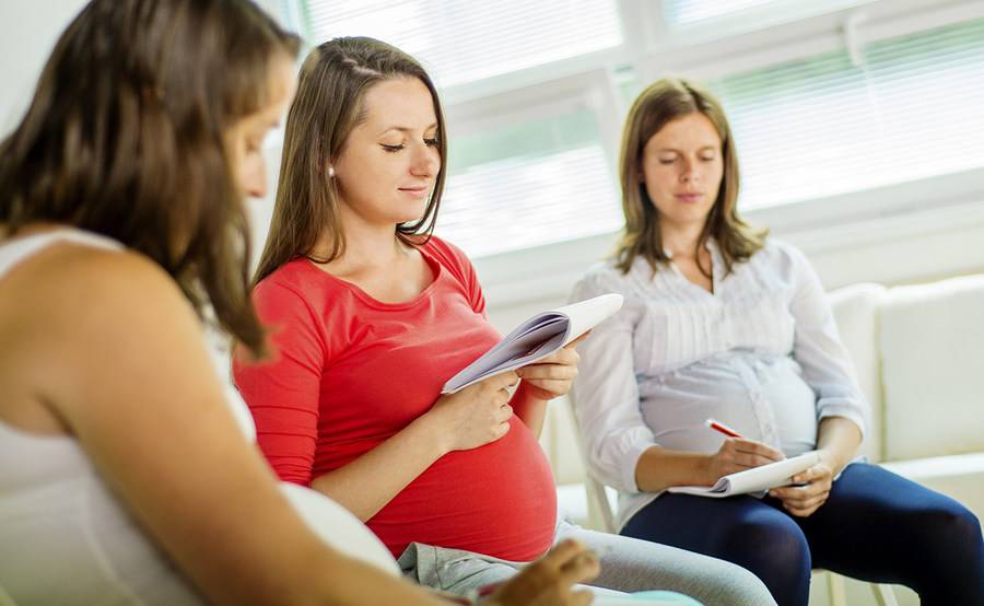 Three pregnant women sitting with notepads.