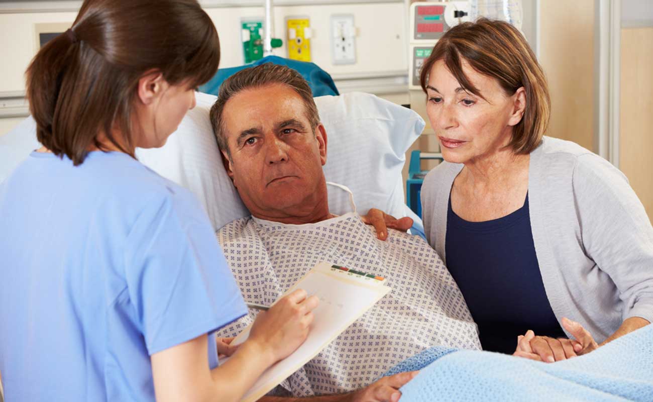 A patient in a hospital bed listens carefully along with a caring family member while a qualified Scripps professional explains the timeline for LVAD procedures.