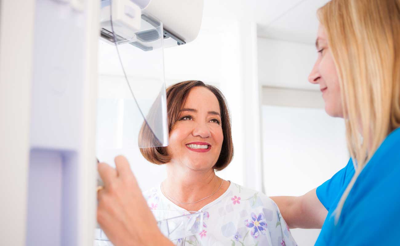 A Scripps technician prepares a middle-aged woman for a mammogram to screen for breast cancer.