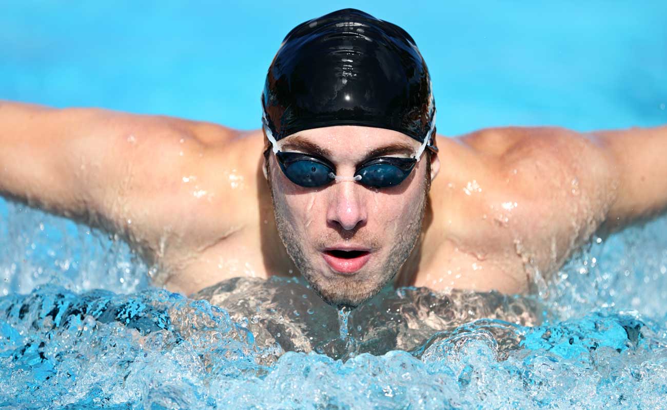 Athletic swimmer wearing a swim cap and goggles in a pool.