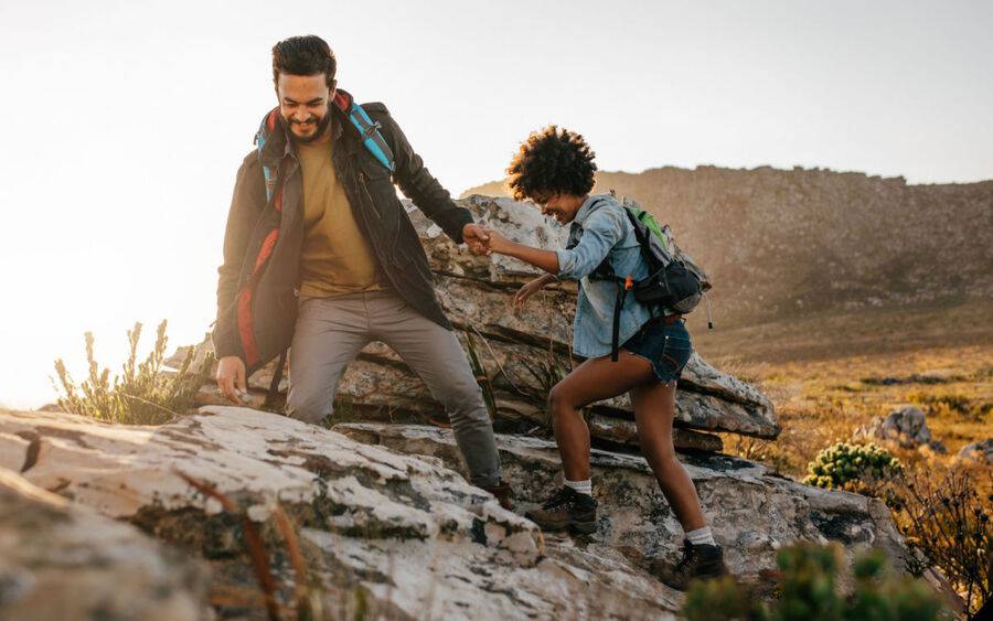 A young African American couple hikes up a mountain.