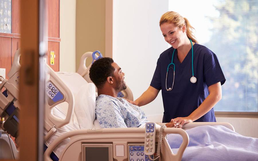 A provider checks on a patient in a hospital room.