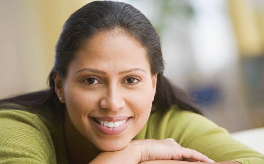A relaxed woman smiles with her arms folded in an indoor setting