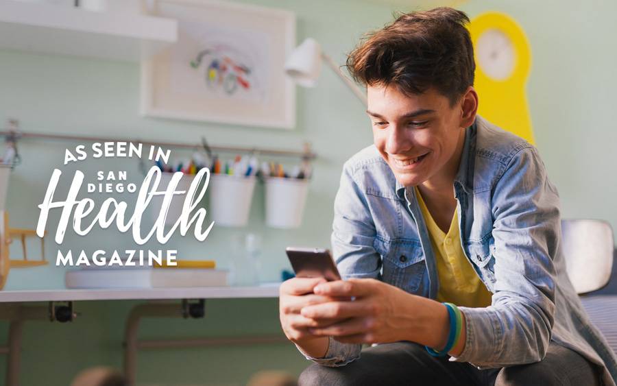 A young man looking at his cell phone demonstrates the need for screen time limits, as studies show people spend hours a day staring at electronic devices.