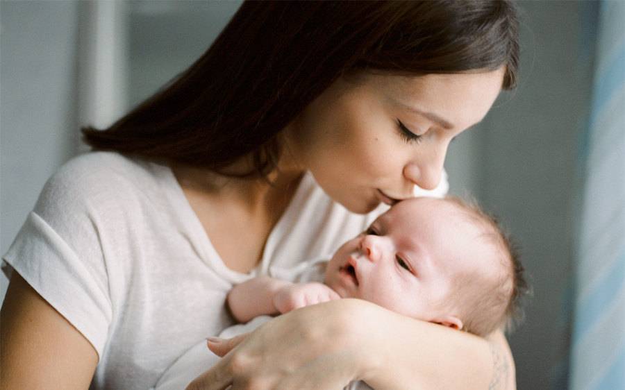 Mother kissing new baby