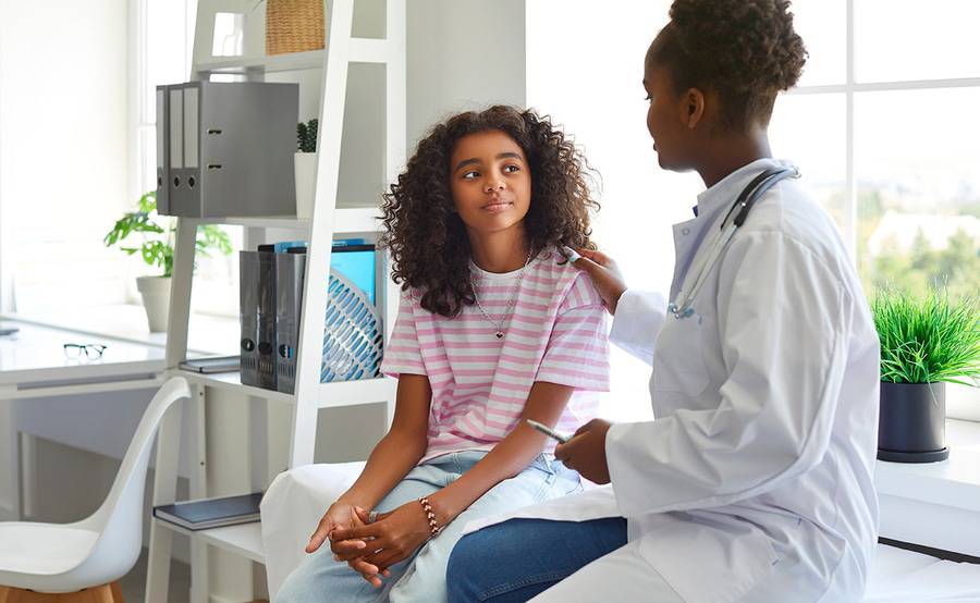 A young black girl and her black doctor discuss how the HPV vaccine lowers cervical cancer incidence.