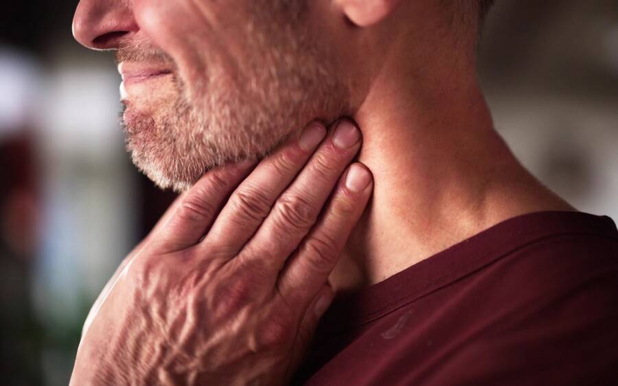 An older man feels his neck for a bump; could it be throat cancer as a result from HPV?