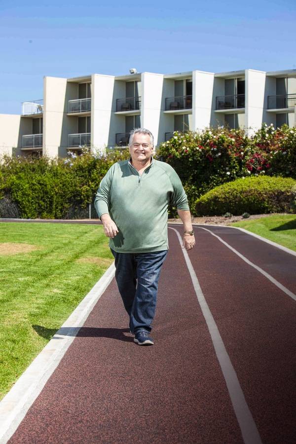 John Rufo walks outdoors on a track.