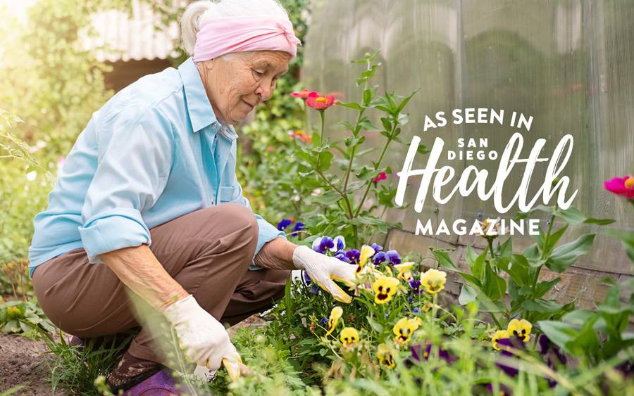 An elderly woman bends down to plant flowers in her garden - SD Health Magazine