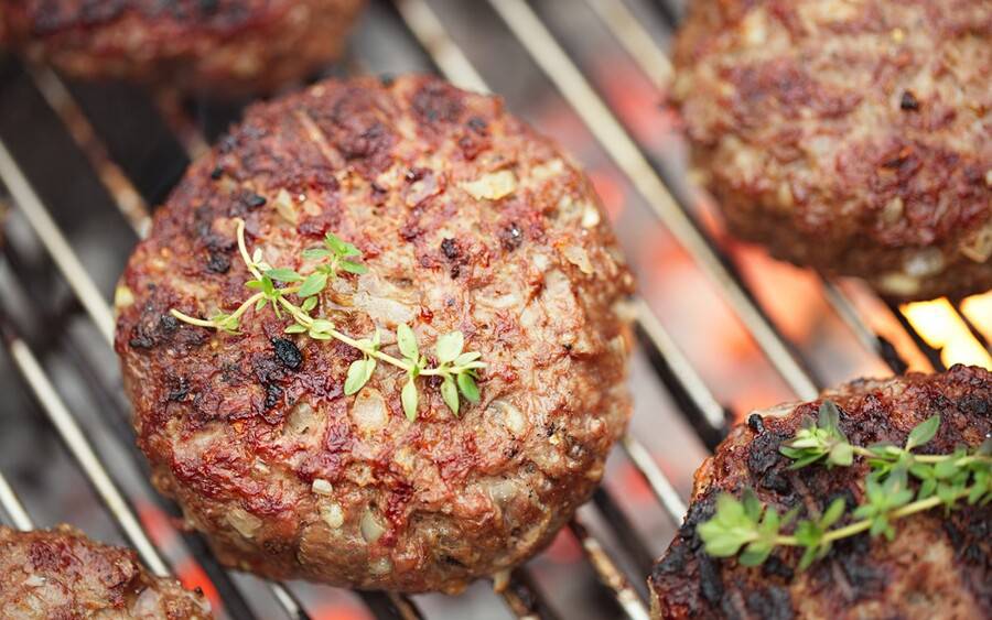 A hamburger getting cooked on a grill.