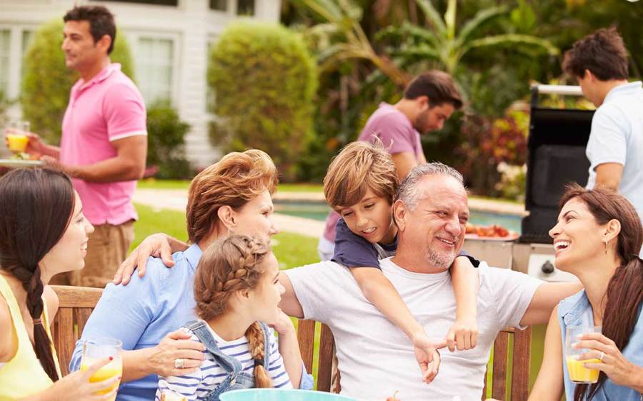 A large family dinner gathering in a San Diego backyard, with a swimming pool and barbecue visible in the background