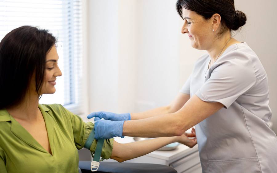 A phlebotomist prepares a woman's arm to have a blood test.
