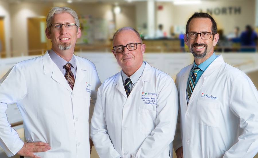 A trio of liver transplant surgeons in white coats stand proud at a Scripps Hospital.