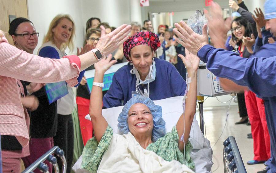 Hospital staff celebrate and high-five a patient  as part of the Scripps Hero Walk program that celebrates living transplant donors.