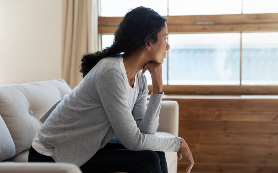 A lonely woman looks outside her window.