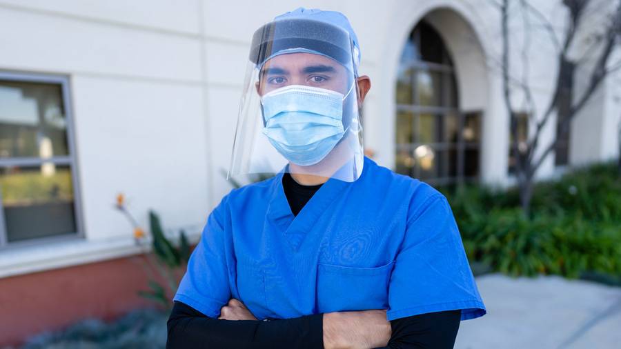 Lucian Mistretta, RN standing outside with a face mask and face shield on, one of the eight Scripps Nurses of the Year 2020.