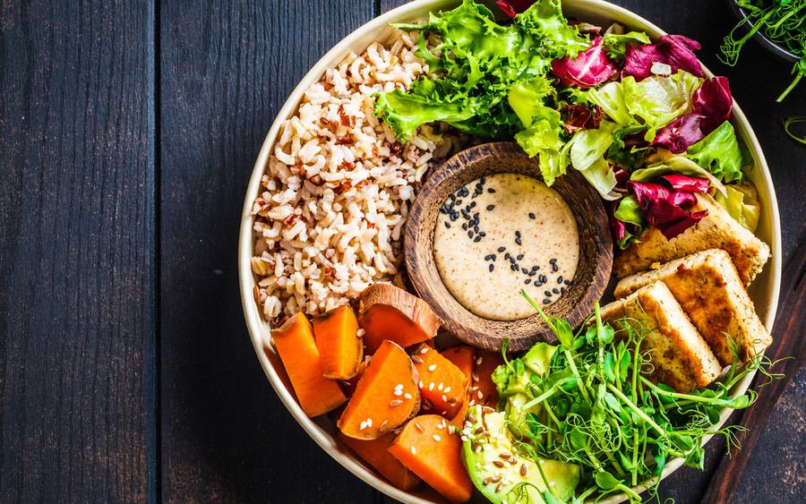 A bowl of whole grains, leafy greens, sweet potatoes, avocado and lean protein.