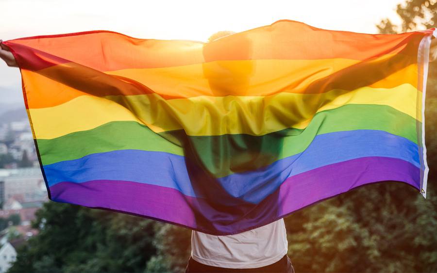 A member of the LGBTQ+ community wraps himself around the pride flag.