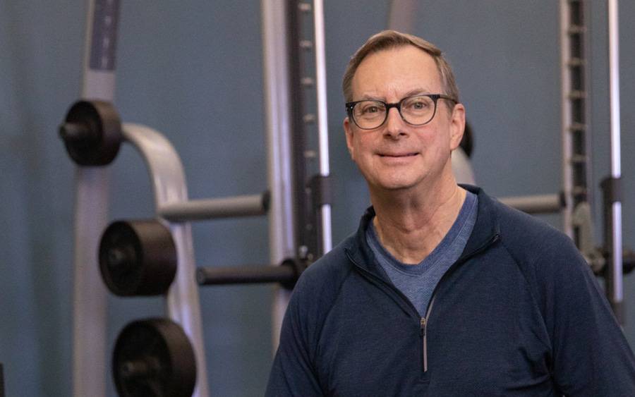 Keith Kendrick smiles near a weight rack  after advanced technology at Scripps helped treat his hereditary heart issue.