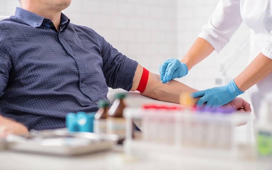 Nurse swabs arm before drawing blood from male donor.
