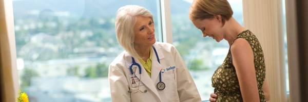 A Scripps maternity health expert talks to a pregnant woman in a bright room in front of a large window, representing the comfortable and convenient birthing locations at Scripps.