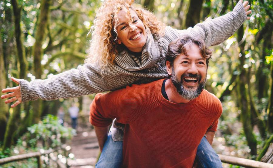 A mature man carrying his partner on his back illustrates life when you can effectively manage your orthopedic pain.