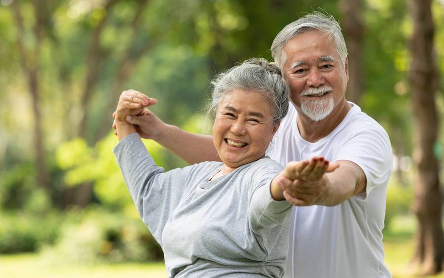 A mature couple is exercising together outside and smiling illustrating quality of life with health joints and tendons.