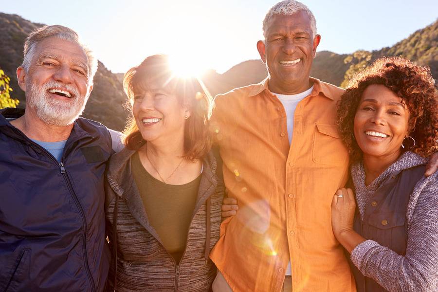 A group of four older adults smile on an outdoors adventure to keep the trail clean.