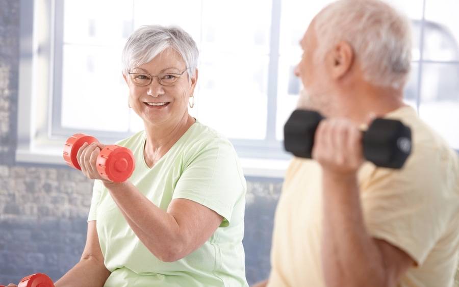 Older couple doing light weights as part of cardiac rehab program.