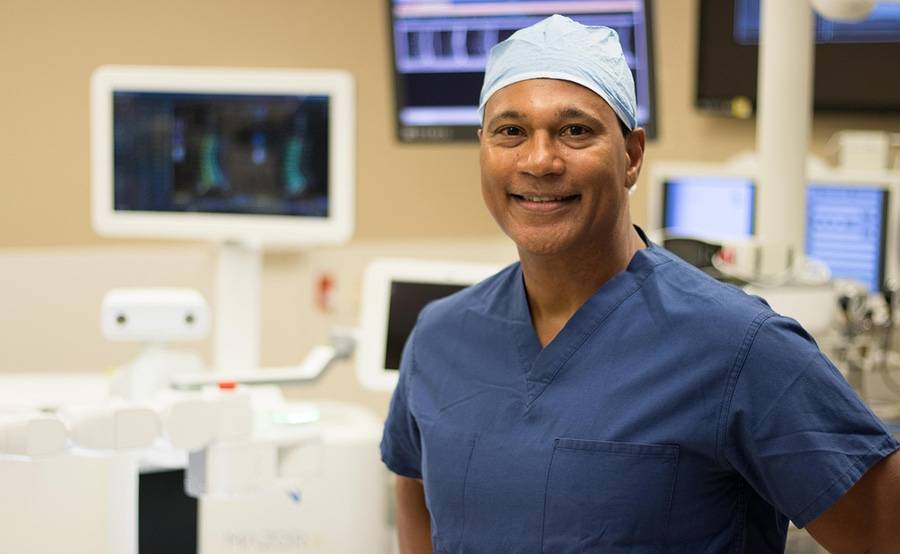 Spine surgeon Neville Alleyne, MD, smiles while standing in the Mazor X spine surgery suite.