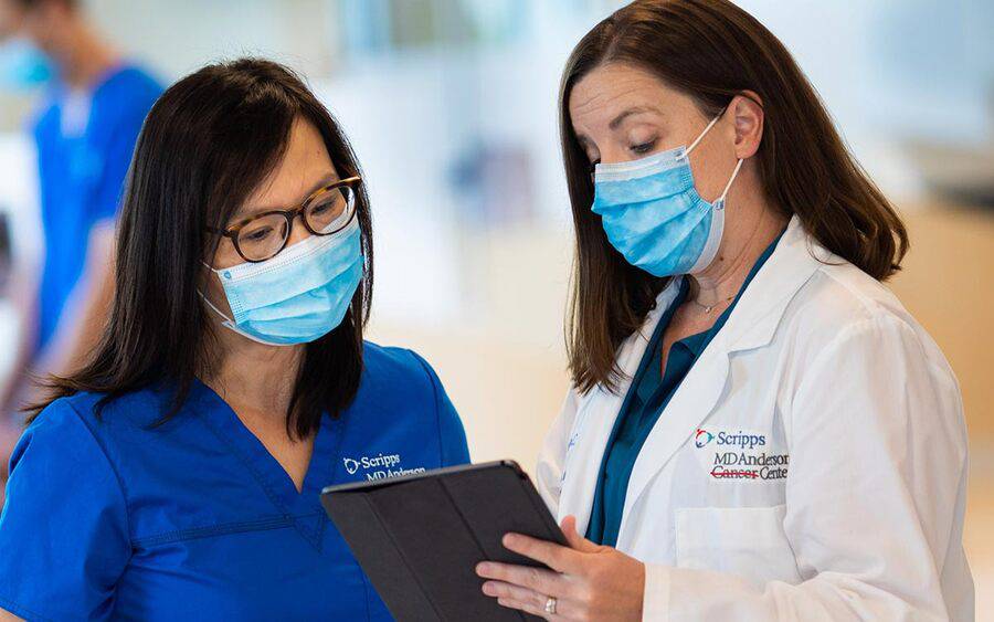 A female doctor (right), and female nurse discuss operational planning at Prebys Cancer Center that gained media coverage.