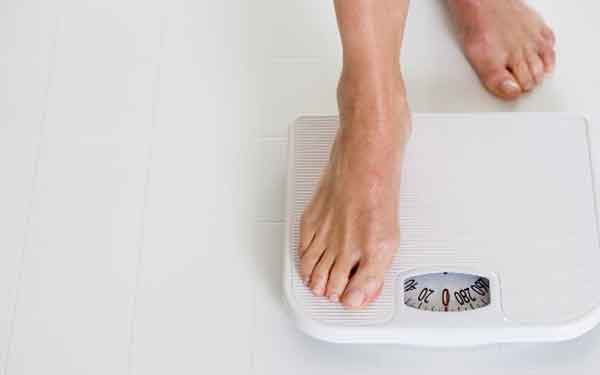 A person prepares to step on a scale to assess their weight loss goals following a minimally invasive weight loss procedure.