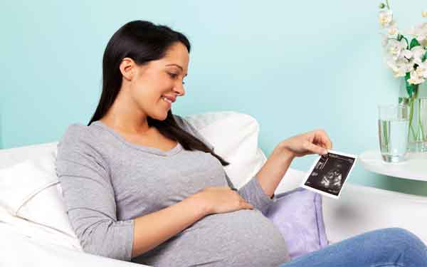 A pregnant woman sits on a couch, representing an expectant parent who might be interested in the Accelerated Childbirth Preparation course at Scripps Health.