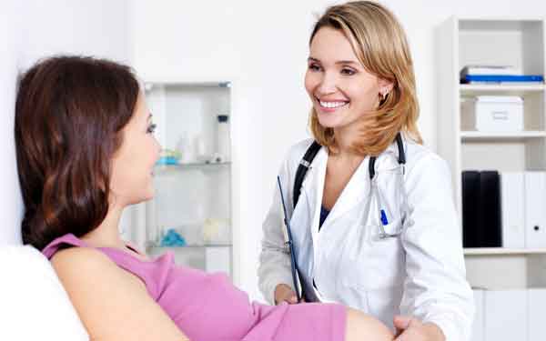 Pregnant woman with smiling doctor at bedside