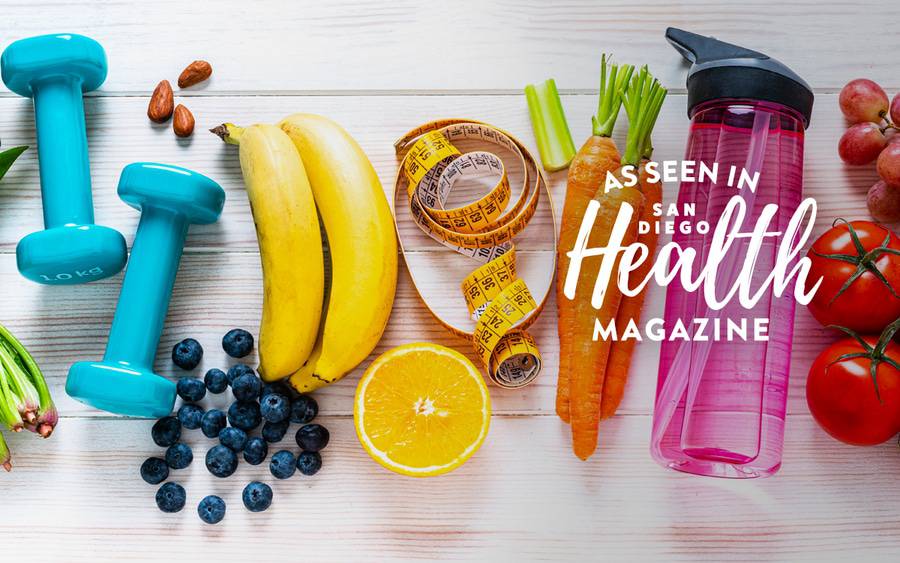 Photo shows a variety of weight management food and tools including light weights, a tape measure, water bottle as well as healthy snacks such as few almonds, blueberries, bananas, carrots, an orange slice and tomatoes.