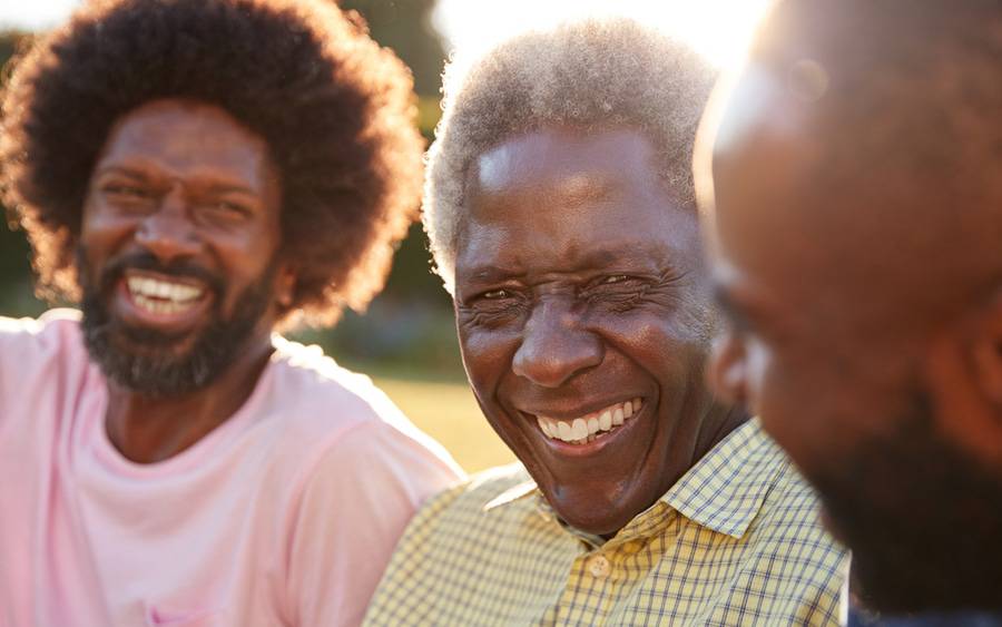 Three black men enjoy a laugh on a beautiful day outdoors.