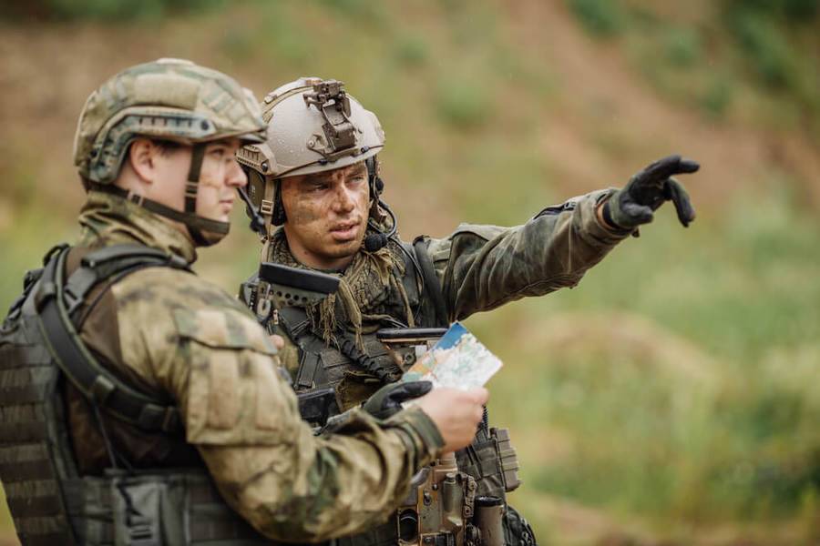 Two men in combat clothing assess a map and how it relates to their immediate surroundings.