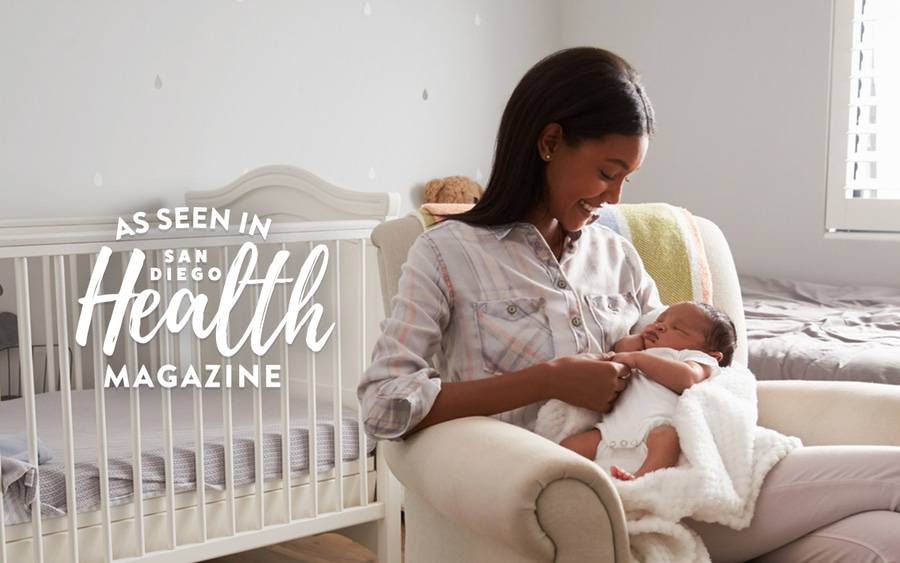 Mother holds a sleeping baby in infant's nursery.